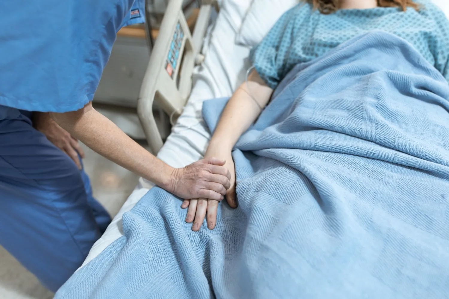 Pflegekraft hält fürsorglich die Hand einer Patientin